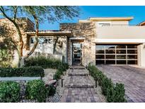 Stunning home featuring stone accents, mature landscaping, and a driveway leading to a glass-paneled garage at 50 Grey Feather Dr, Las Vegas, NV 89135