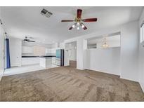 View of open-concept living room with a ceiling fan that connects to the kitchen with white cabinets at 8529 Gold Flash Ave, Las Vegas, NV 89129