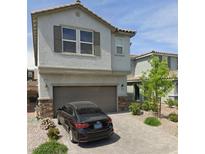 Two-story home featuring a two-car garage, stone accents, a tiled roof, and a paved driveway with nice landscaping at 10163 Kings Amethyst St, Las Vegas, NV 89141