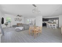 Bright open-concept living room and kitchen features a large sectional couch, dining table, and a modern kitchen with stainless steel appliances at 412 Gracious Way, Henderson, NV 89011