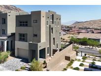 Modern, multi-story home with a muted color palette and a well-manicured front yard and a mountain backdrop at 11658 Midnight Melody Ave, Las Vegas, NV 89138