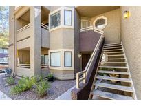 Condo with a private entrance, stairway, and a small landscaped area with shrubbery in front of the building at 5052 S Rainbow Blvd # 201, Las Vegas, NV 89118