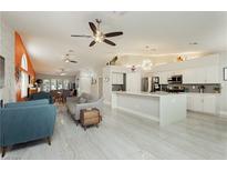 Open-concept living room with tile floors, ceiling fans, and white kitchen with island at 6100 Cocktail Dr, Las Vegas, NV 89130