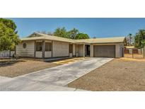 Single-story home with stucco exterior, two-car garage, gravel landscaping and long concrete driveway at 671 Riata Way, Las Vegas, NV 89110
