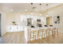 Modern kitchen featuring white cabinetry, stainless steel appliances, a quartz countertop island, and stylish pendant lighting at 1006 Blue Lantern Dr, Henderson, NV 89015