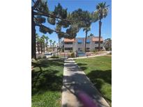 Charming condo complex featuring lush landscaping, palm trees, and blue awnings over the windows on a sunny day at 101 Luna Way # 104, Las Vegas, NV 89145
