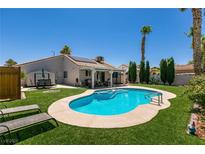 Inviting backyard with a sparkling blue pool, green grass, and covered patio perfect for relaxation at 5025 Chambliss Dr, Las Vegas, NV 89130