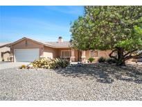 Charming single-story home featuring a well-manicured yard with desert landscaping, mature trees, and an attached garage at 5060 Wheatland Dr, Pahrump, NV 89061