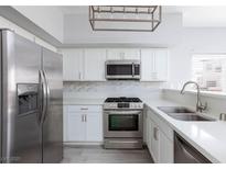 Bright kitchen featuring stainless steel appliances, white cabinets, and a stylish tile backsplash at 4820 Grey Wolf Ln # 101, Las Vegas, NV 89149