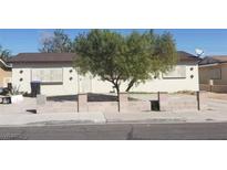 Beige single story home features a tree and security bars over the windows at 1936 Lawry Ave, North Las Vegas, NV 89032