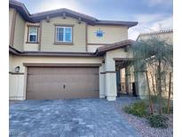 Two-story home with tan siding, brown trim, a two car garage, and a beautiful brick paver driveway at 302 Bay Village Pl, Henderson, NV 89011