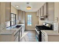 Well-lit kitchen features stainless steel appliances, modern cabinetry, mosaic tile backsplash, and bright quartz countertops at 4805 Nara Vista Way # 203, Las Vegas, NV 89103