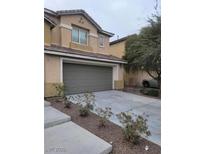 Two-story tan home featuring an attached garage, complemented by fresh landscaping and a spacious driveway at 3237 Perching Bird Ln, North Las Vegas, NV 89084