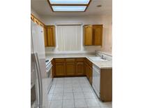 Traditional kitchen with white appliances, tile floors, and wood cabinets offering ample storage at 438 Fountain Grove St, Henderson, NV 89012