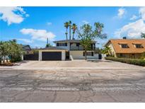 Two-story home with a black roof, black garage door, palm trees and desert landscaping in front at 2724 Natalie Ave, Las Vegas, NV 89121