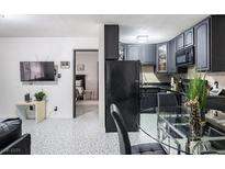 Open-concept living room with modern gray kitchen, glass dining table, and view into the bedroom at 4955 Jeffreys St # 605, Las Vegas, NV 89119