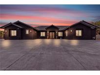 Elegant single-story home featuring a dark exterior, tile roof and a spacious concrete driveway at 6235 N Fort Apache Rd, Las Vegas, NV 89149
