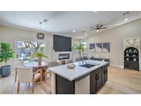 Open-concept living room and kitchen with an island, fireplace, wood floors, and modern decor at 7772 Buckwood Ct, Las Vegas, NV 89149