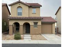 Two-story stucco home featuring an attached garage, arched entryway, and low maintenance landscaping at 12021 Spice Tree St, Las Vegas, NV 89183
