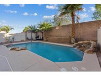 Sparkling pool area with rock waterfall feature, desert landscaping and pergola for outdoor entertaining at 8325 Winterchase Pl, Las Vegas, NV 89143