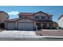 Two-story home featuring a three car garage, tile roof, and a low maintenance front yard at 6449 Elizabethtown Ave, Las Vegas, NV 89110
