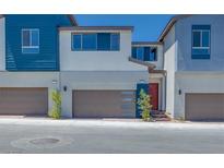 Modern townhome featuring a two-car garage, contemporary design, and a red front door at 2523 Campaldo St, Henderson, NV 89044