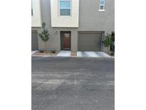 Neutral-toned townhome featuring a garage, front door, and minimalist landscaping at 2755 Atomic Tangerine Way # 2, Las Vegas, NV 89183