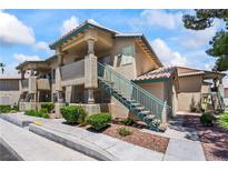 A cozy condo exterior with stone facade, desert landscaping, and blue staircase at 338 Jett St # 101, Las Vegas, NV 89145
