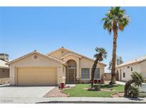 Charming single-story home featuring a two-car garage, desert landscaping and mature palm trees at 5580 Lonesome Biker Ln, Las Vegas, NV 89113